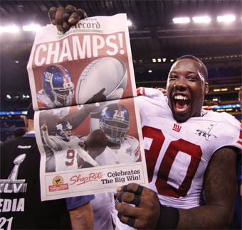 Jason Pierre-Paul holds up a newspaper following the New York Giants' Super Bowl win.