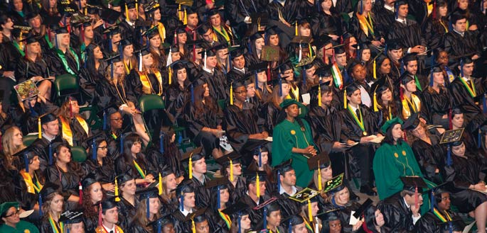 Graduating students sitting in caps and gowns at commencement