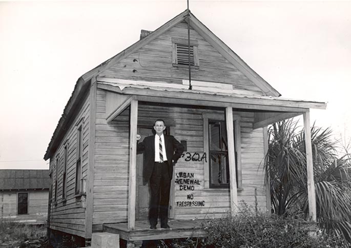 Sam Gibbons stands on the porch of a house.