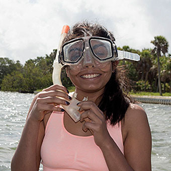 A student wearing goggles and a snorkel smiles.