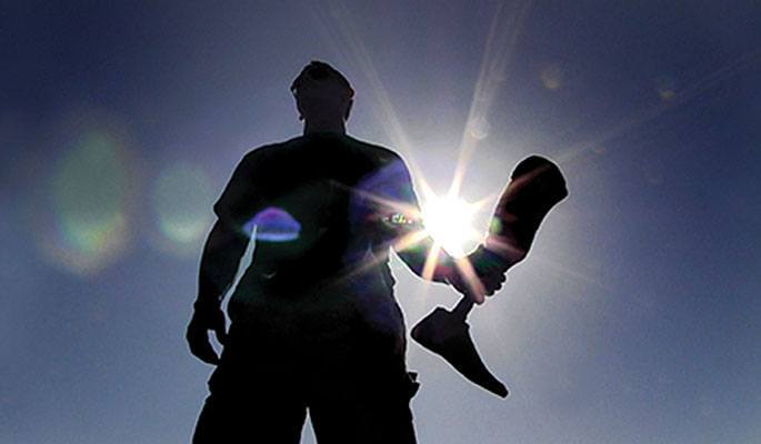Silhouette of Joshua Sparling holding a prosthetic leg.