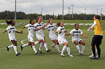 USF women's soccer team runs toward their goalie on a soccer field.