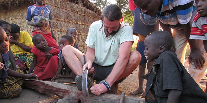 Anthony Pooley uses a saw while children watch.