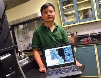 Associate professor Chuanmn Hu shows satellite images on a laptop.