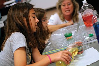 Young girls participate in an activity using colored liquids.